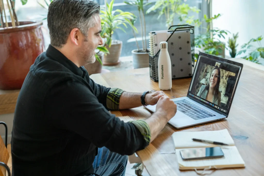 A man at a table with a laptop and a plant, focused on his gluco-keto online coaching session